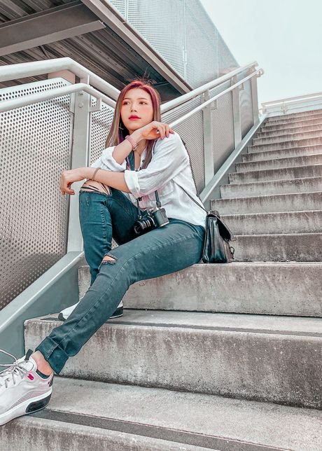 Phuong Nguyen, graphic designer, seated on a staircase with a camera